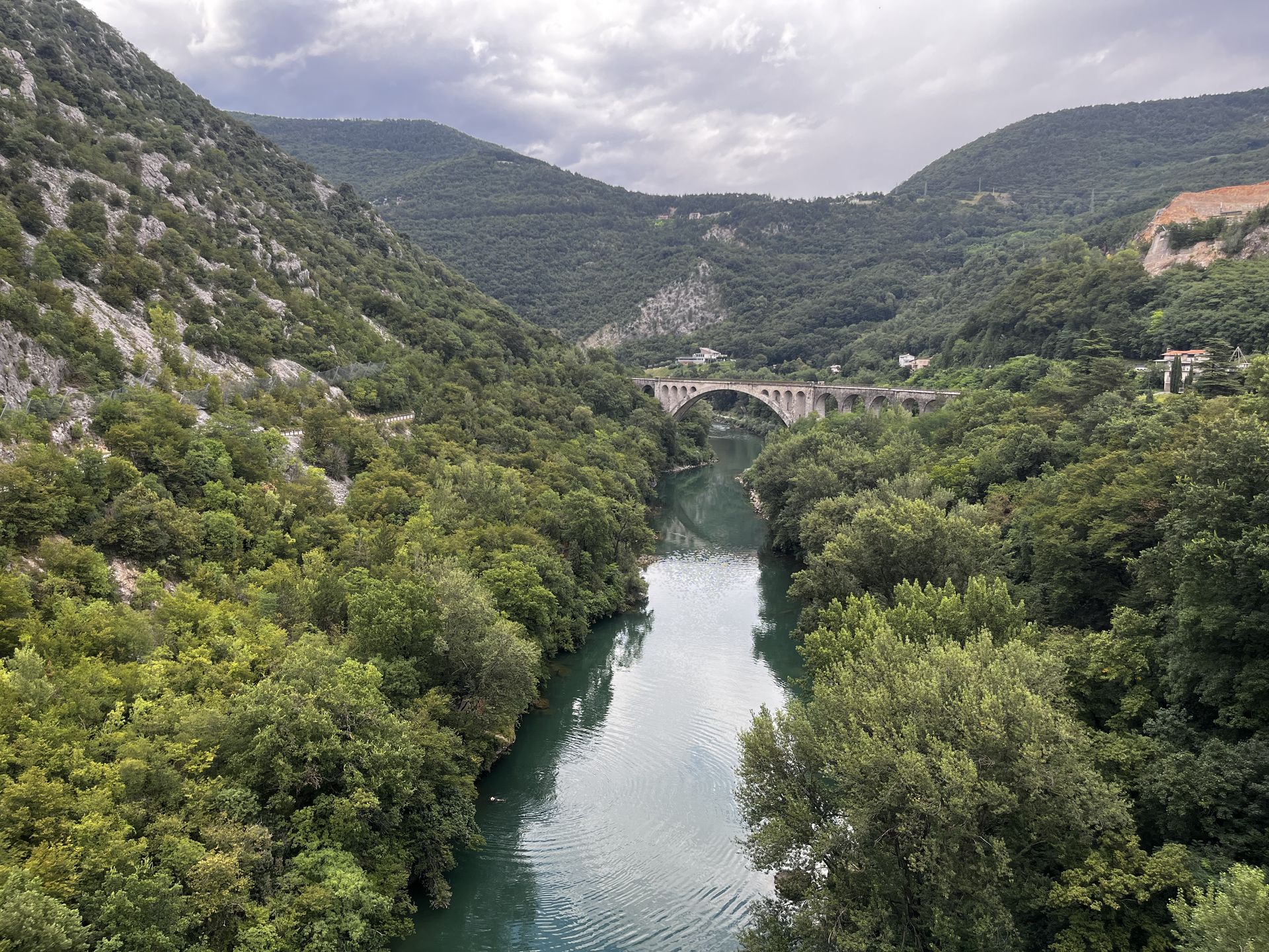 View od solkan bridge from a nearby car bridge with soca river and trees all around it