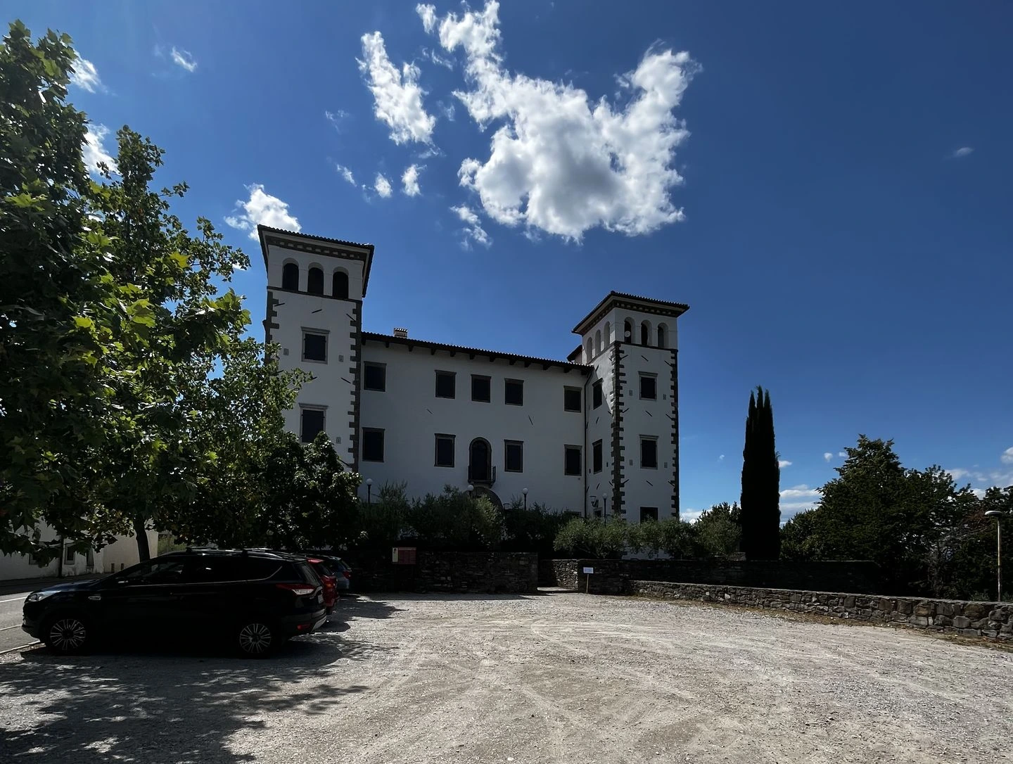 view of castle dobrovo from gravel parking with trees
