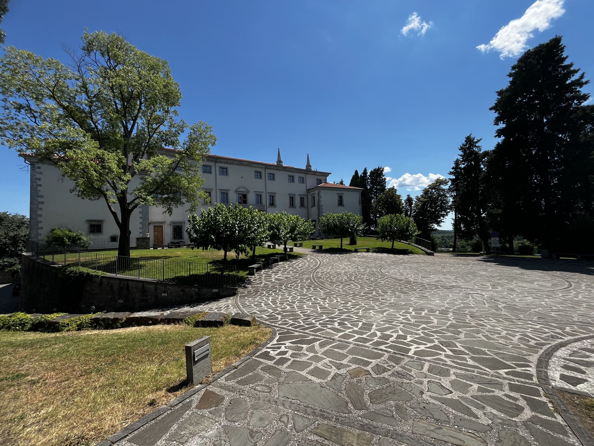 View of Villa Vipolže surrounded by trees and a stone square in front