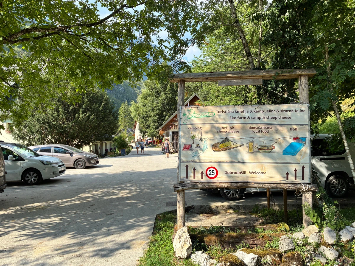 Sign for Jelinčič farm and camp with a gravel parking and trees