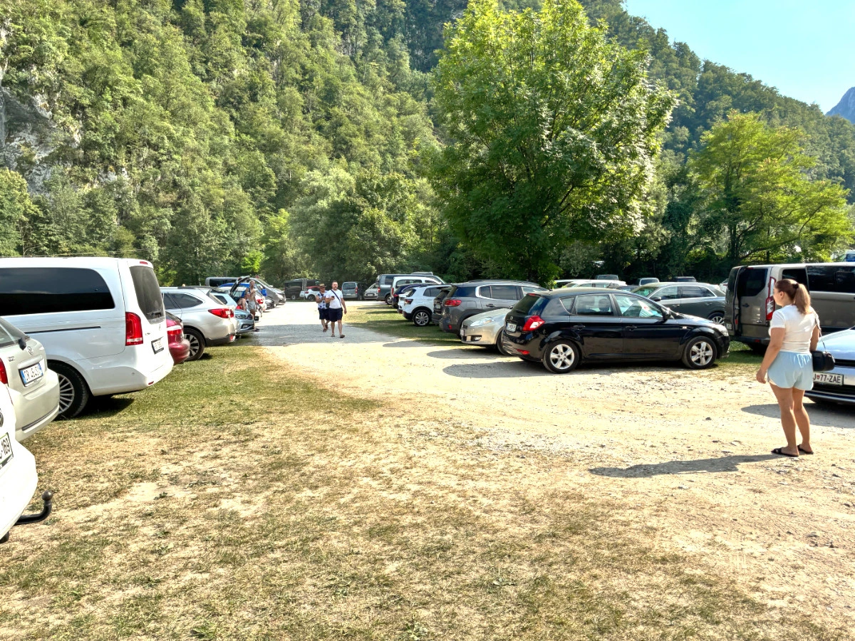 Gravel and grass parking filled with cars at Robič bathing area