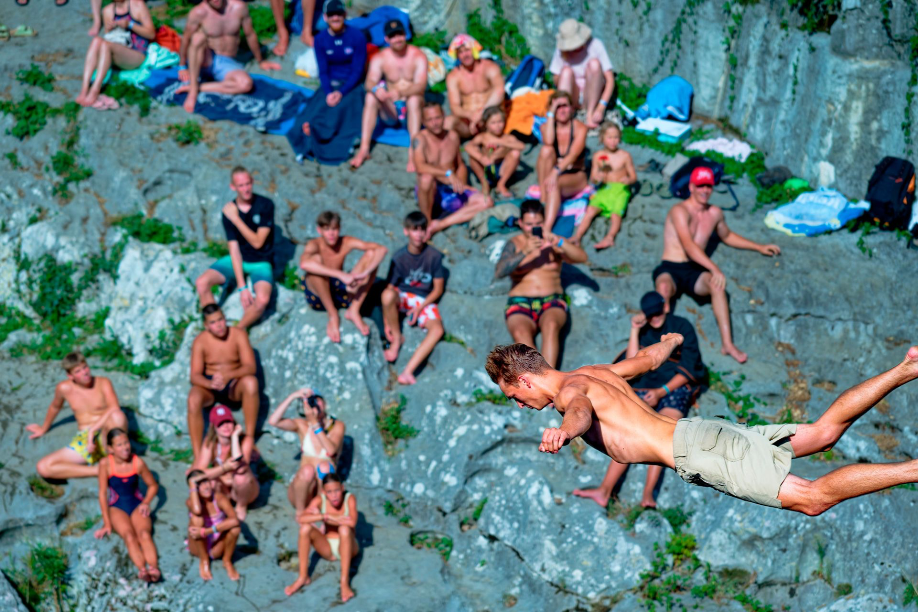 Audience sitting in the river and on the beach watching the diving competition.